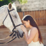 Elegant girl in a long white dress. Lady with horse