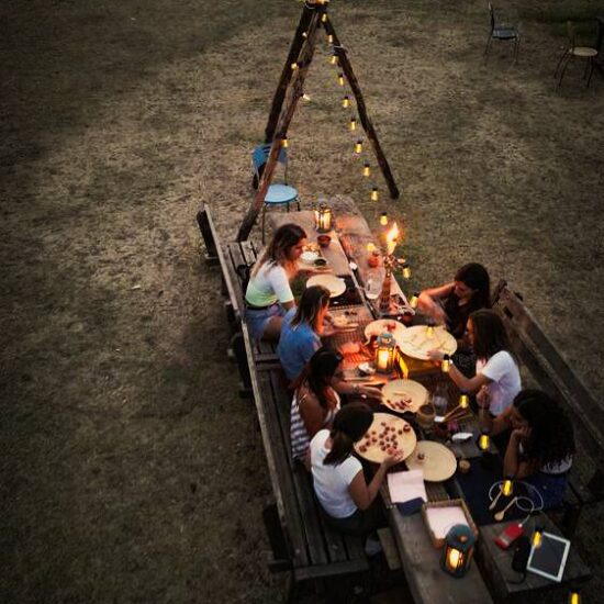 gruppo di ragazze fa un aperitivo allestito con luci e candele, nel parco nazionale del Vesuvio