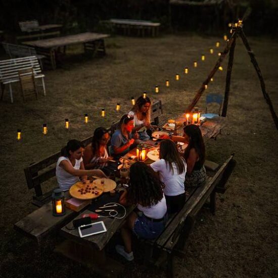gruppo di ragazze a lume di candela che fanno un aperitivo ai piedi del Vesuvio