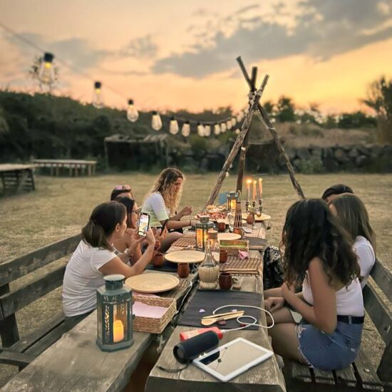 gruppo di ragazze fa un aperitivo allestito con luci e candele, nel parco nazionale del Vesuvio