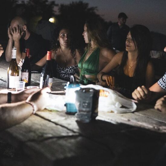 ragazzi parlano a tavola di notte con torce da campeggio nel parco del Vesuvio