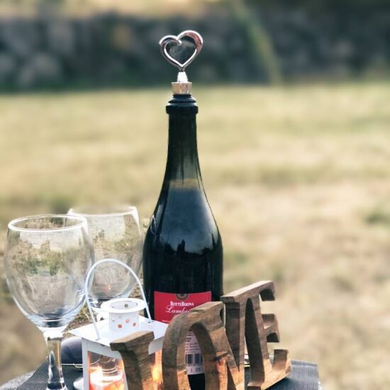 una bottiglia di vino e due calici con la scritta love in un area verde del Vesuvio
