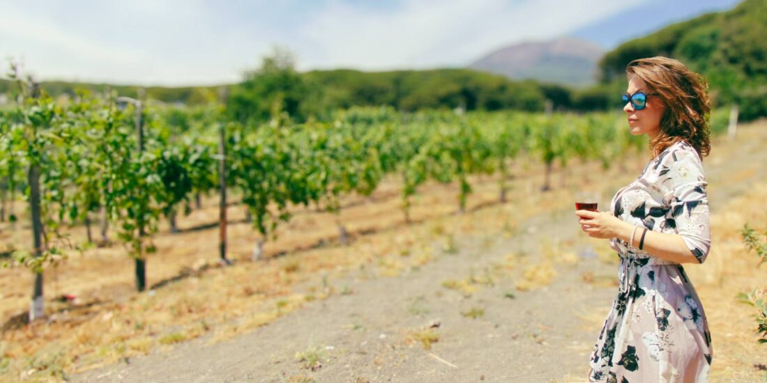 bellissima ragazza beve un bicchiere di vino in un vigneto del Vesuvio