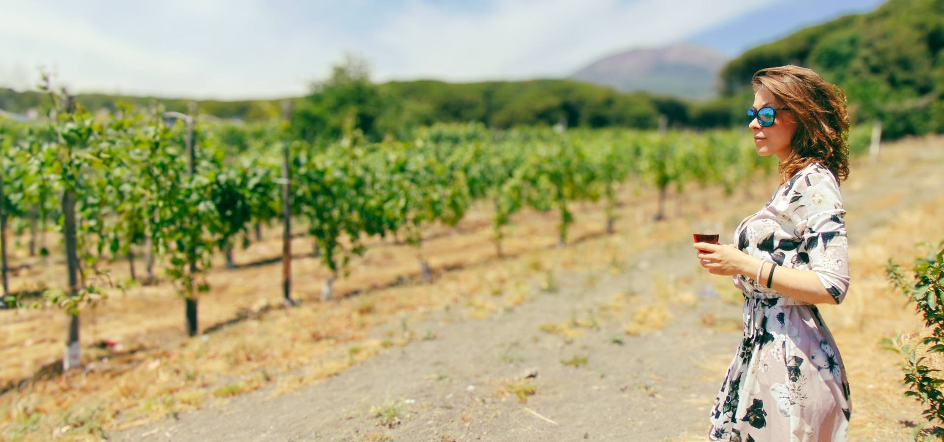 bellissima ragazza beve un bicchiere di vino in un vigneto del Vesuvio