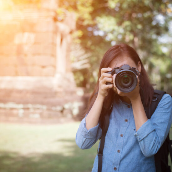 Young attractive woman photographer tourist with backpack coming to shoot photo at ancient temple in Naples